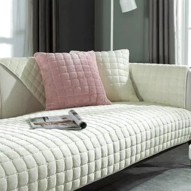 Velvet quilted sofa cover in cream with pink quilted cushion on a living room couch.