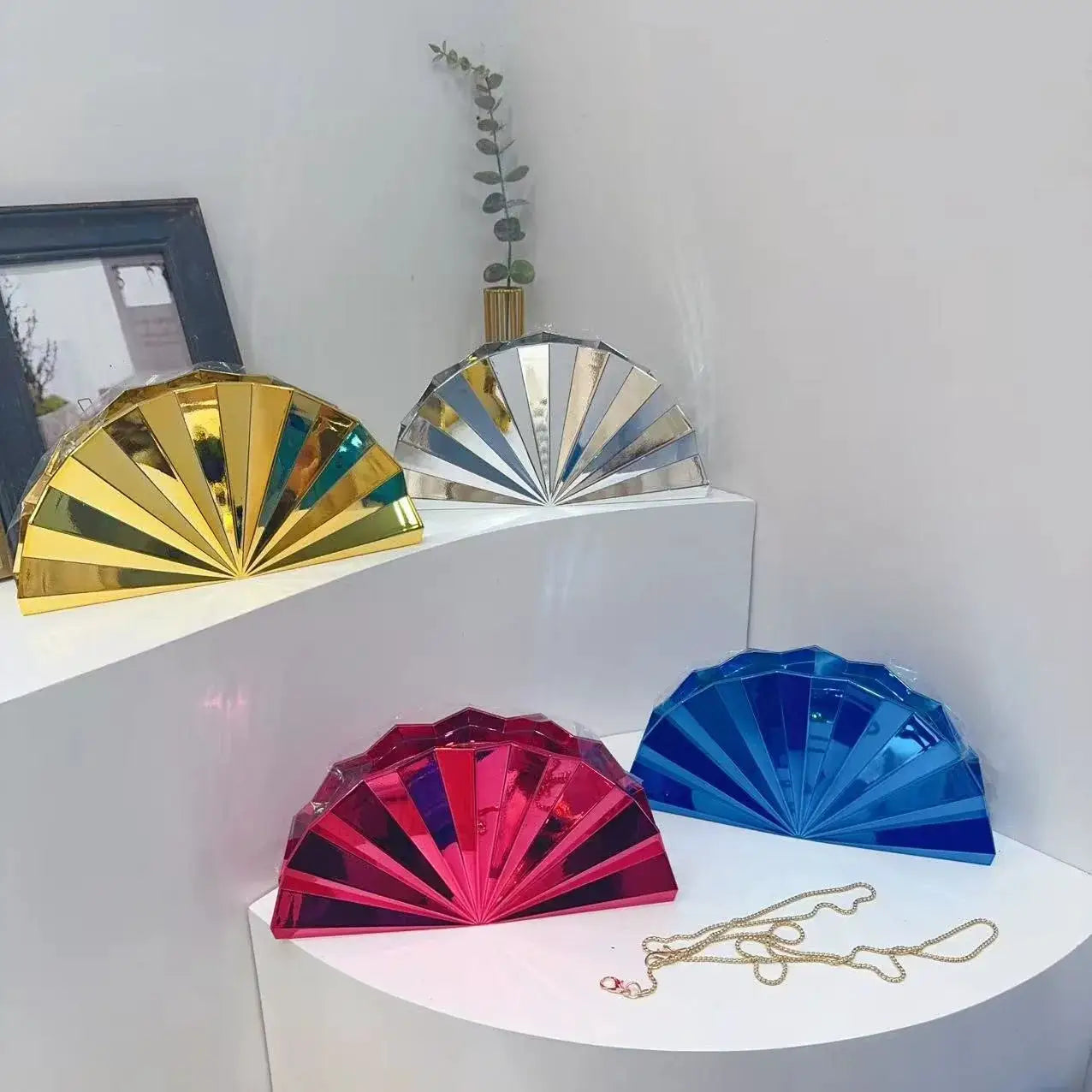 Five moon-shaped acrylic purses in gold, silver, pink, blue and red with matching chain straps