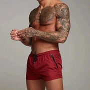 Men's red swim trunks with black zippered pockets and drawstring