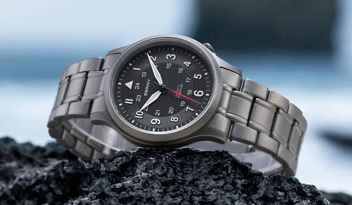 BERNY full titanium men’s field watch on rock with black dial, luminous hands, sapphire crystal, metal bracelet