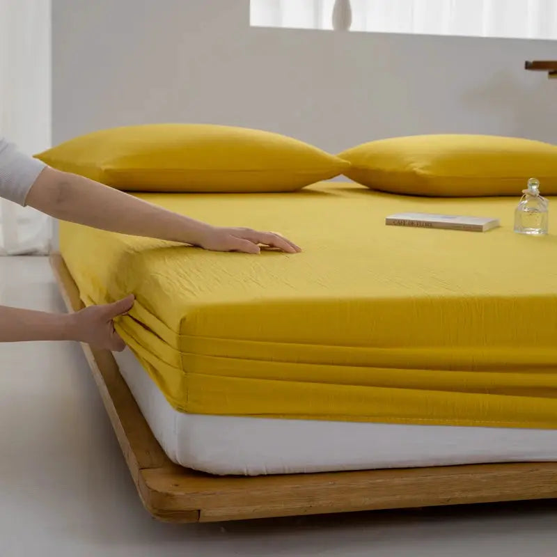 Soft cotton fitted sheet by Simples Market, yellow with elastic band on bed