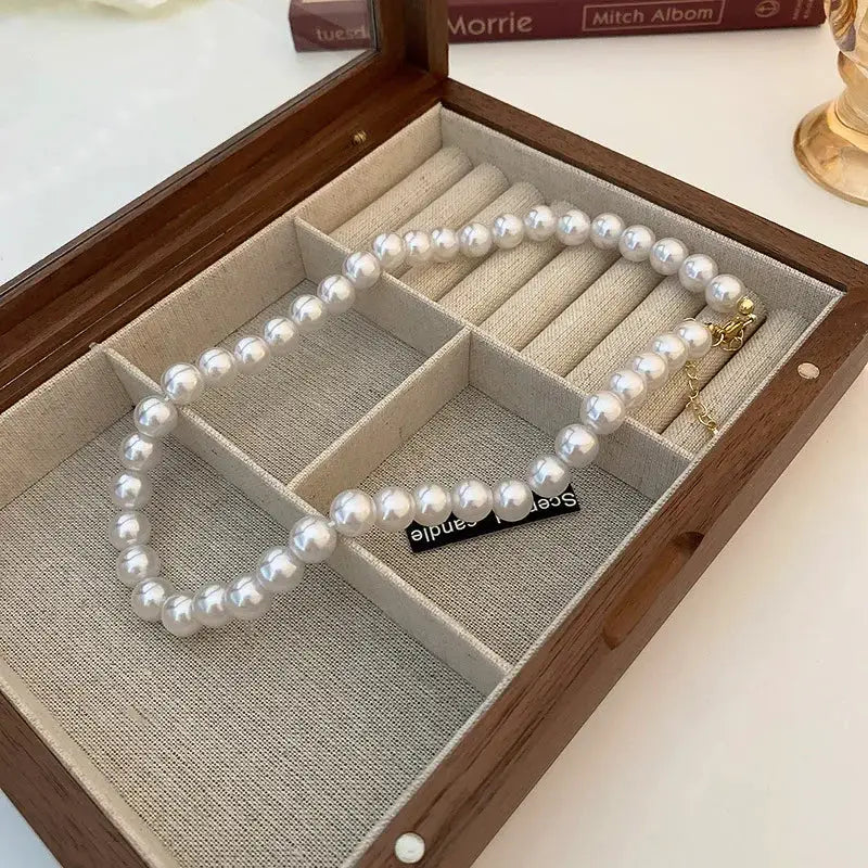 Imitation pearl necklace in a wooden jewelry box; white faux pearls with gold clasp
