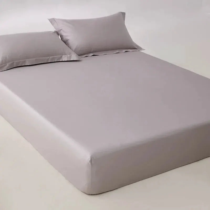Egyptian cotton fitted sheet in light gray on a bed with two pillows, size 160/200.