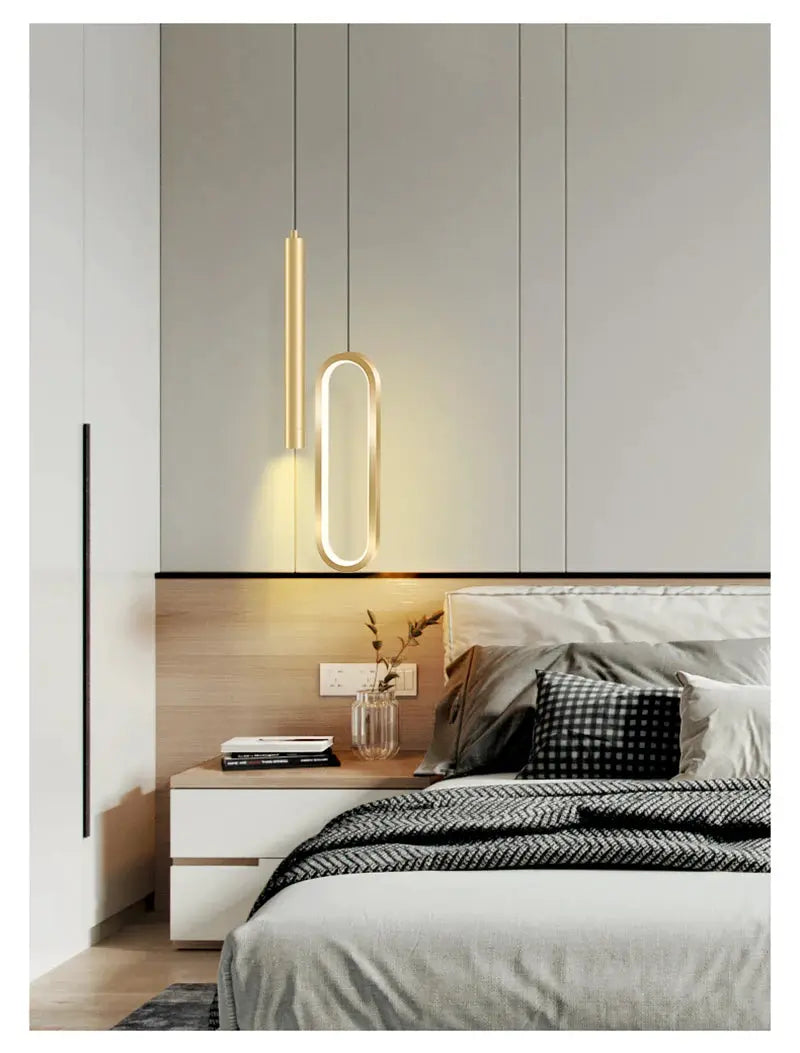 Nordic LED hanging pendant lights in gold finish, two in a modern bedroom with warm glow above bedside table.