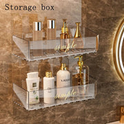 Clear acrylic bathroom storage rack mounted on marble wall with cosmetic bottles and gold-toned accessories