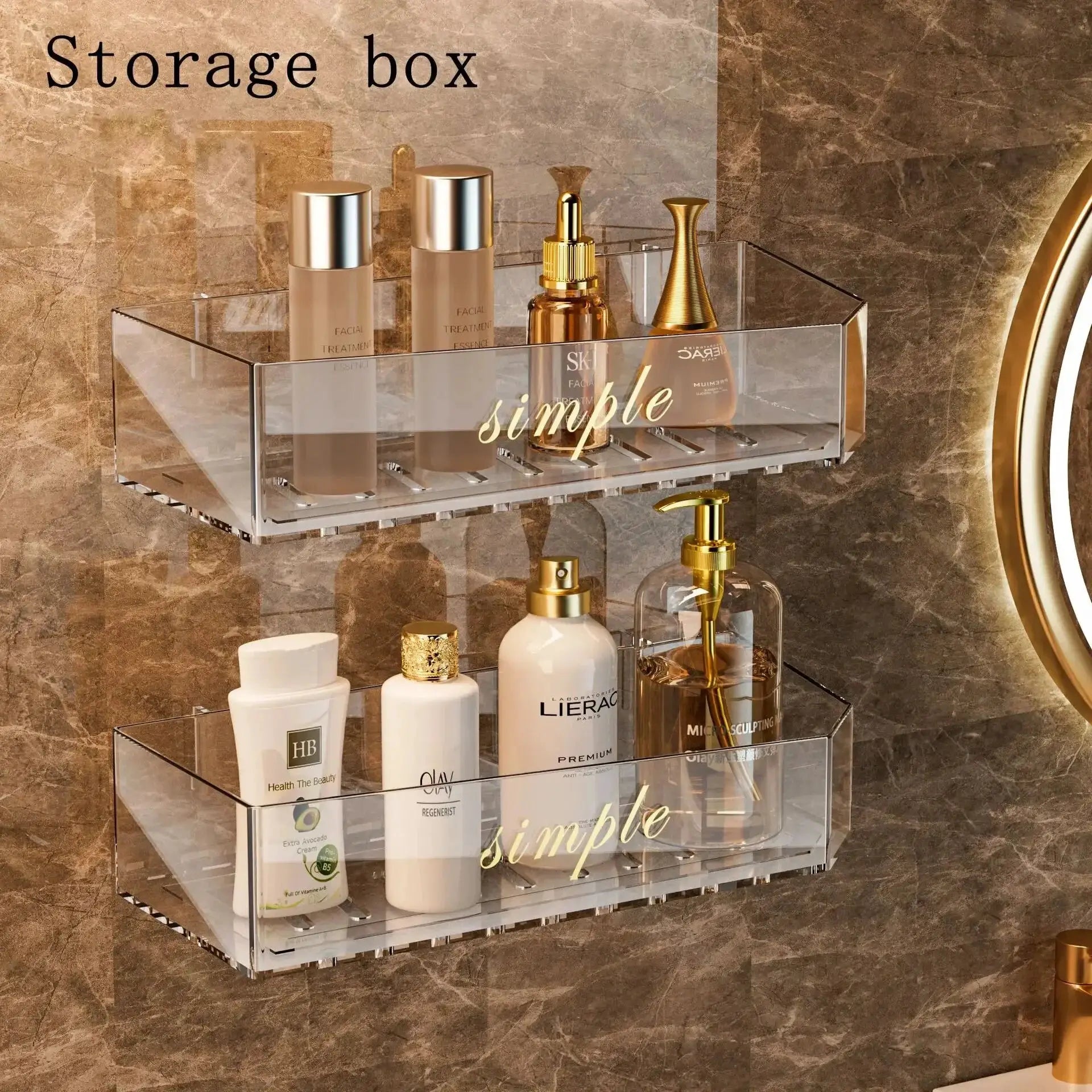 Clear acrylic bathroom storage rack mounted on marble wall with cosmetic bottles and gold-toned accessories