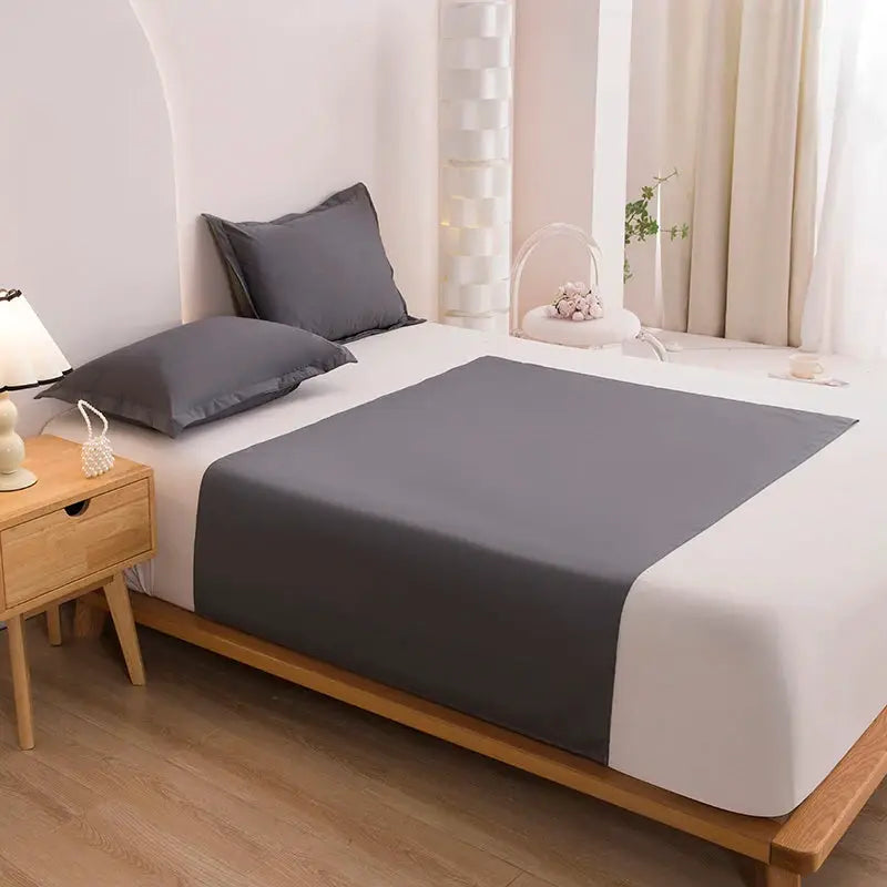 Bed flat sheet TPU waterproof mattress cover in dark gray by Simples Market on a white bed.