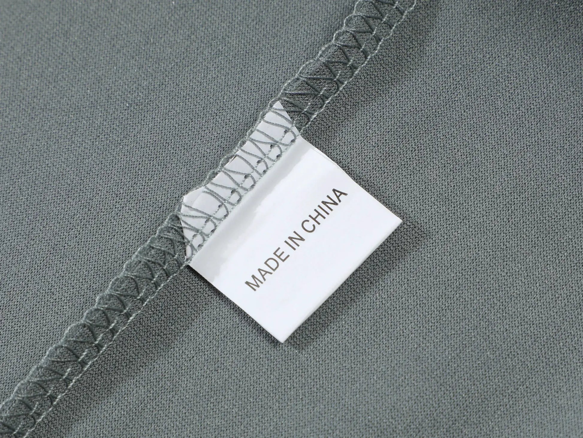 Men's gray polo shirt fabric close-up showing stitched seam and Made in China tag