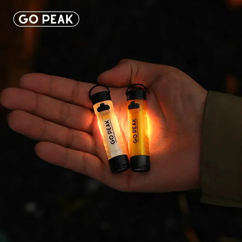 GO PEAK pocket mini flashlights with key clips; two amber LEDs glow in hand.