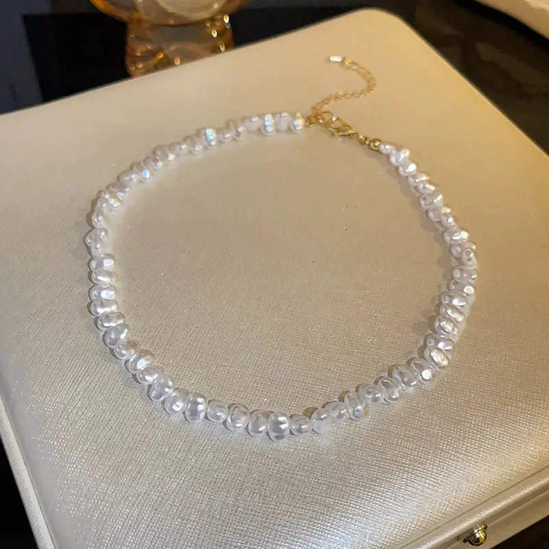 Imitation pearl necklace for women, white pearl-like beads on a collarbone-length choker with a gold extender chain.