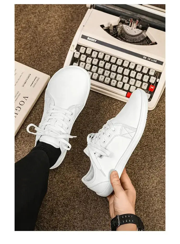 White wide-version barefoot shoes for men and women, lightweight flat walking sneakers on brown carpet