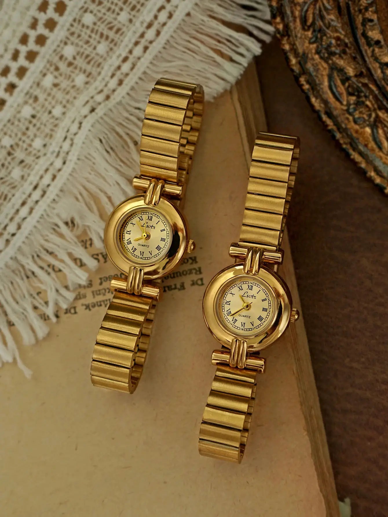 Two gold-toned women's wristwatches with Roman numeral dials and linked bracelet bands.