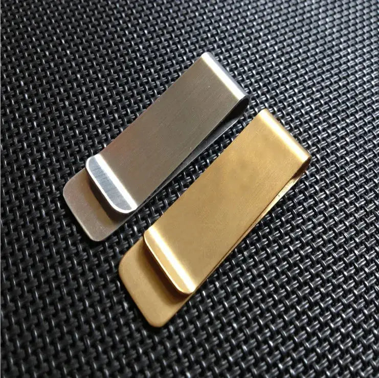 Two metal money clips in silver and gold-tone on a black textured surface.