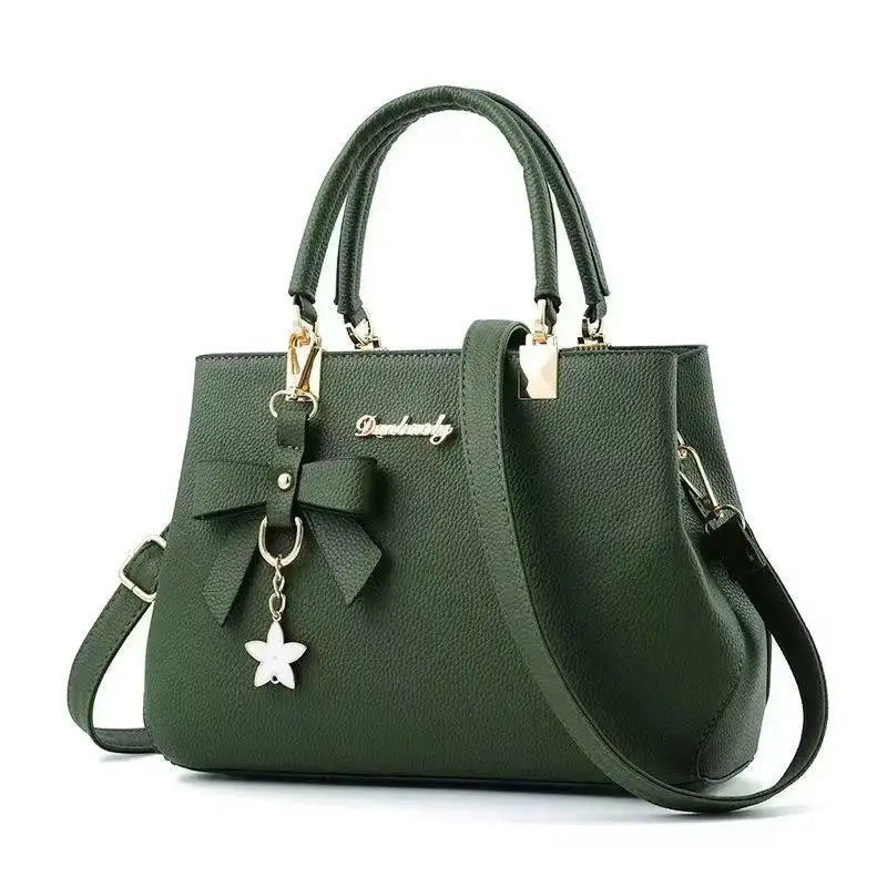 Green pebbled leather bow handbag with double top handles, detachable shoulder strap, and star charm