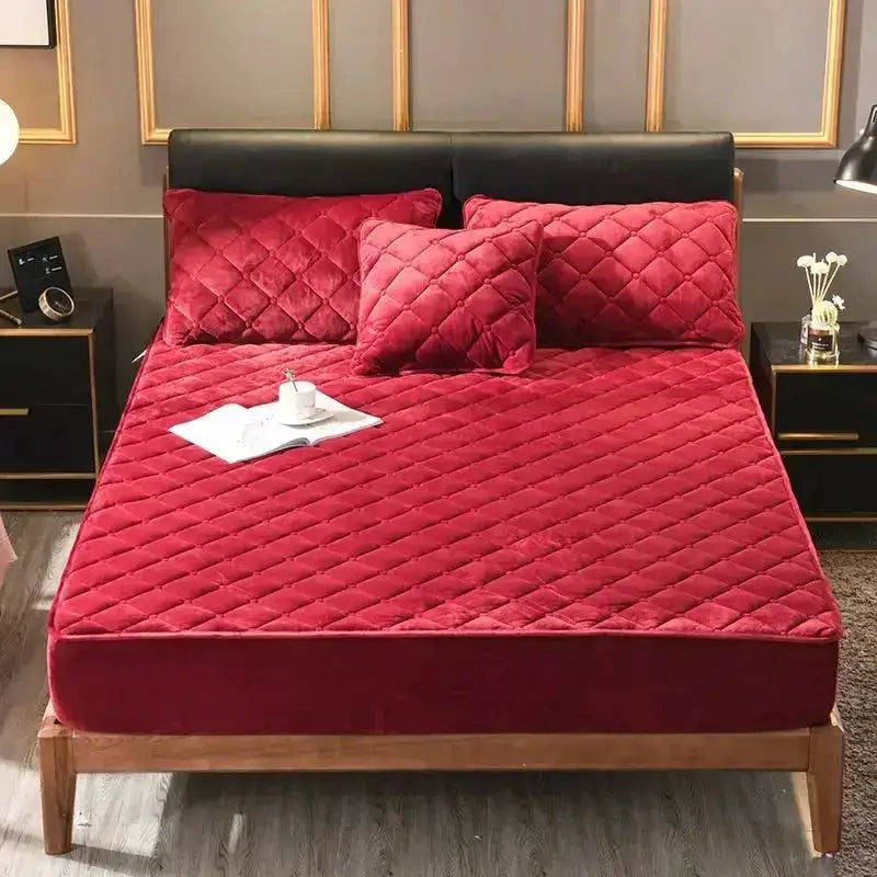 Quilted mattress cover in red crystal velvet with three matching pillows on a wooden bed frame.