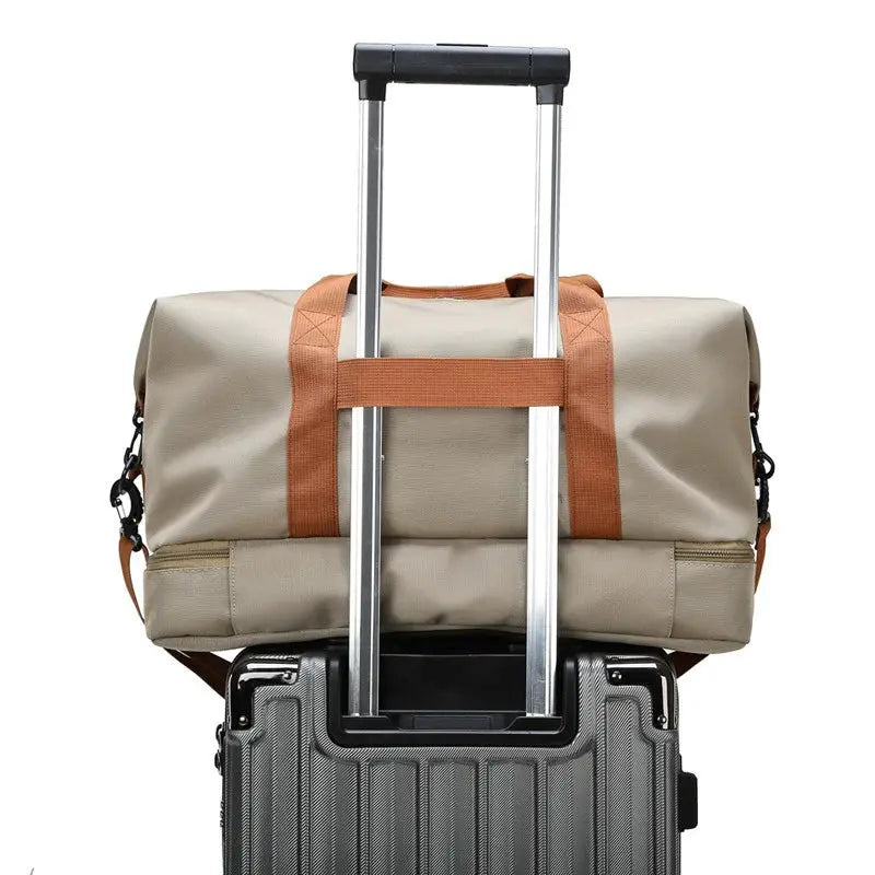 Simples Market expandable travel duffle bag in beige with brown straps atop a wheeled suitcase