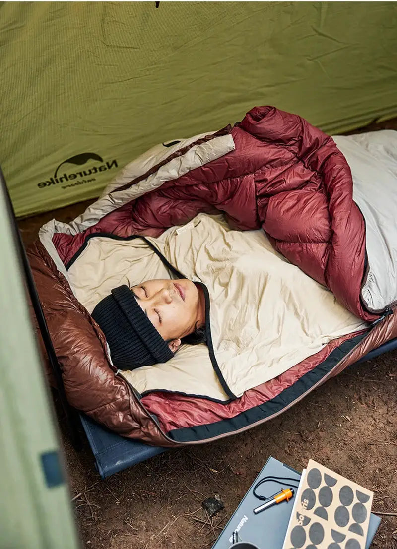 Naturehike sleeping bag liner in maroon outer shell with beige interior, worn by person inside a tent.