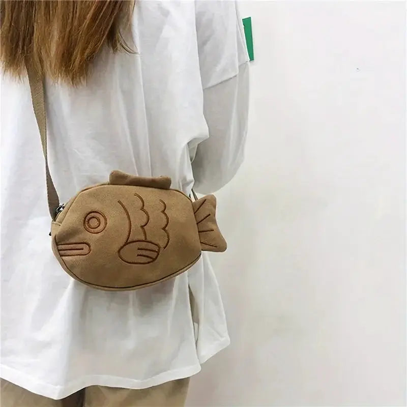 Fish-shaped canvas crossbody bag with embroidery, tan color, zippered pocket.
