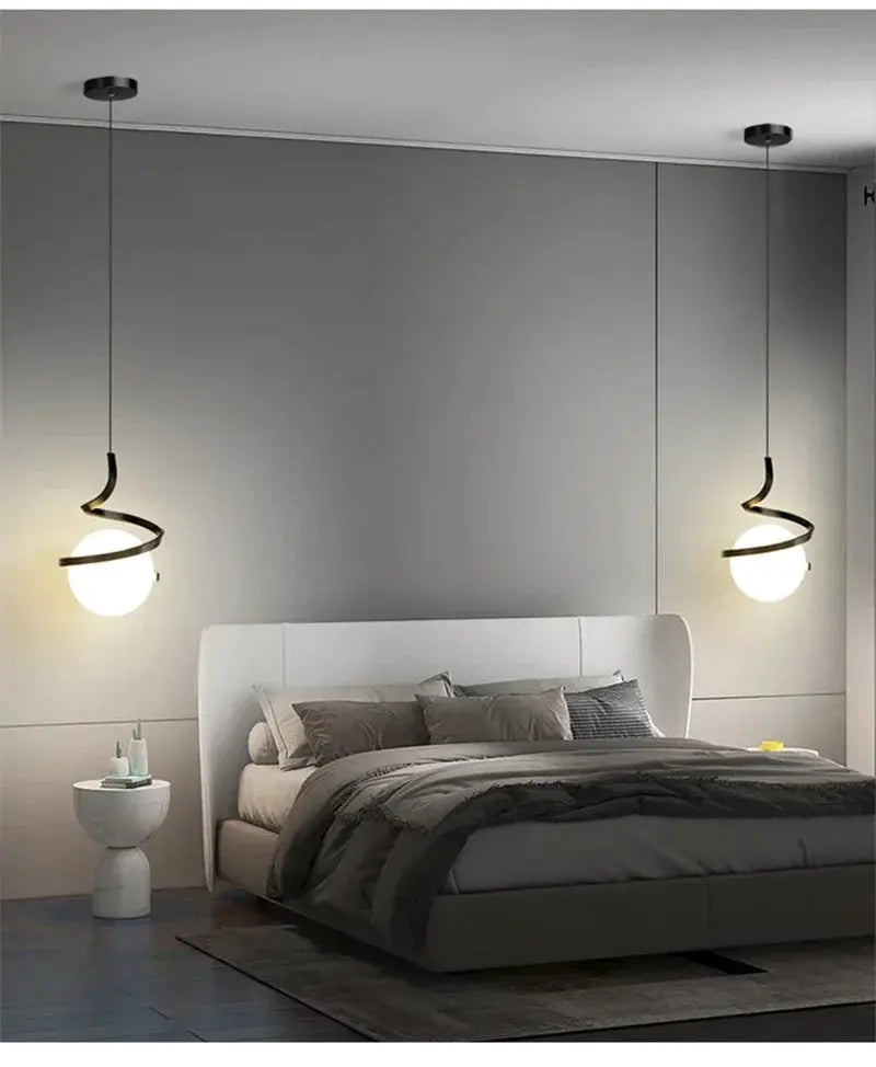 Nordic LED pendant light pair by Simples Market, double spiral black metal suspensions with globe bulbs over a gray bed.