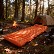 Simples Market orange 4-inch thick camping sleeping pad laid beside campfire and tent