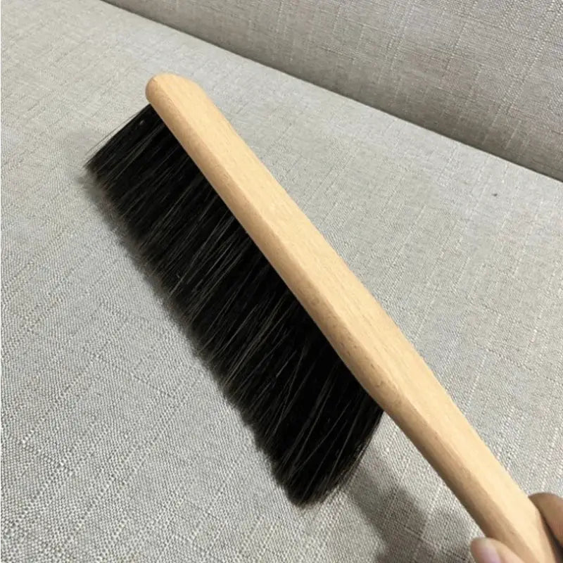Wooden-handled cleaning brush with black bristles for dusting and sweeping.