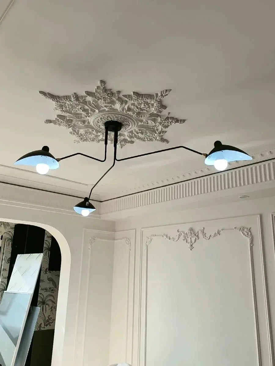 Modern spider pendant light with black arms and blue dome shades, ceiling mount in an ornate white living room.
