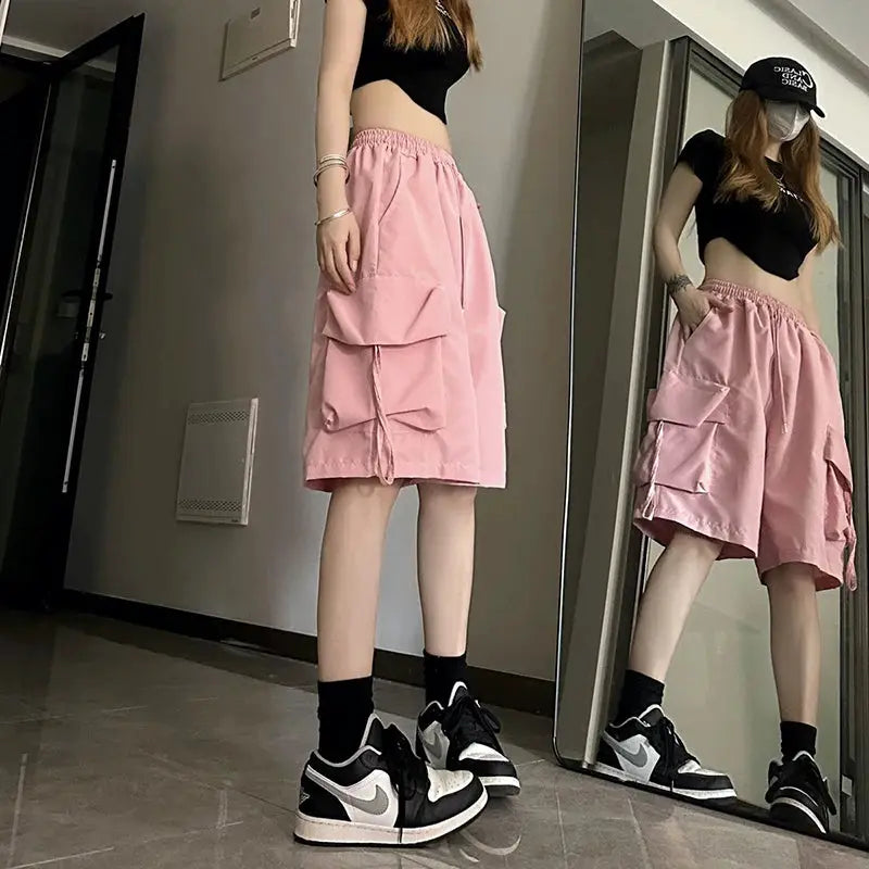 ZOKI pink high-waisted cargo shorts with large side pockets, loose wide-leg streetwear style.
