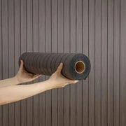 Self-adhesive wood-grain wallpaper roll in dark brown, held by hands.