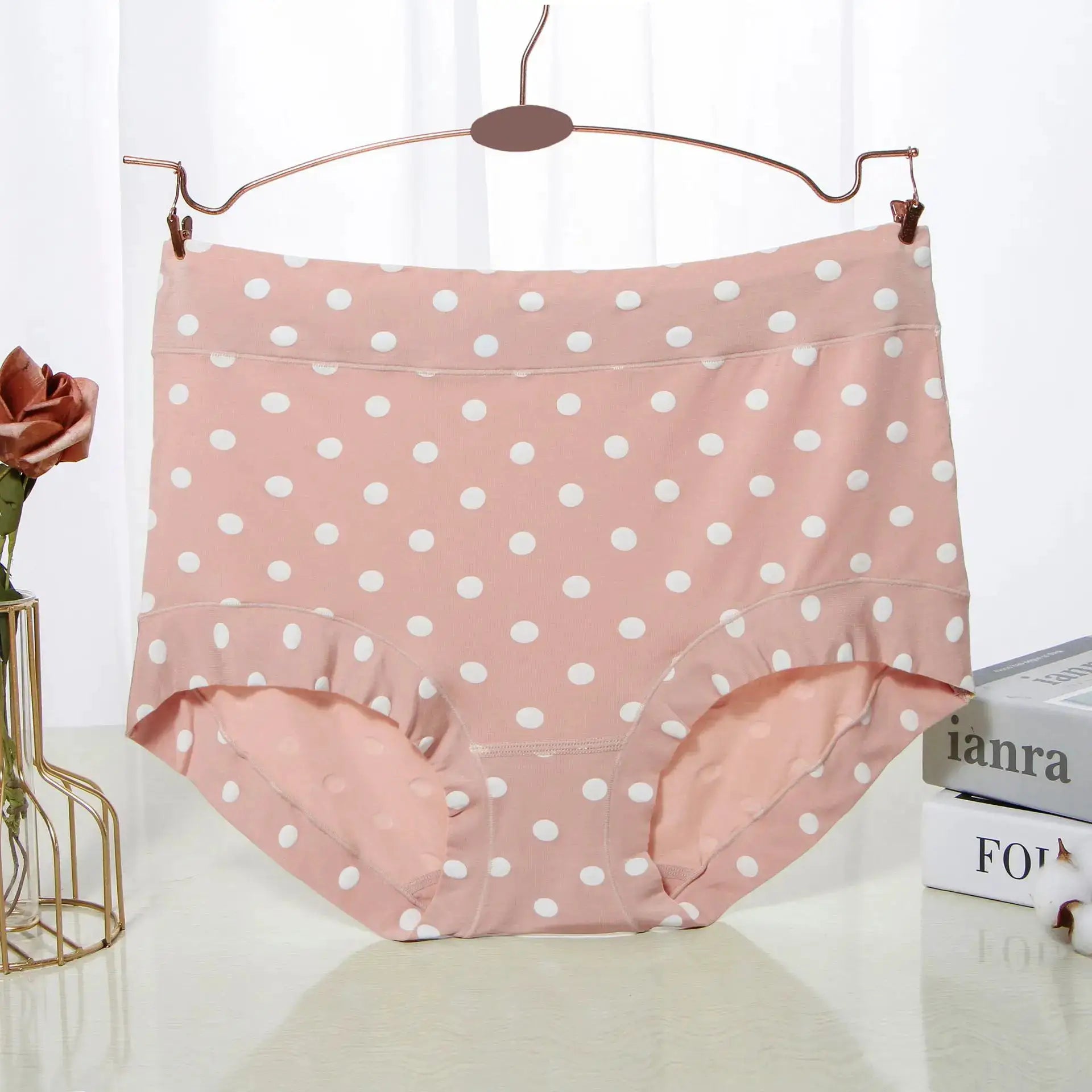 Pink polka dot high-waist panties hanging on a copper hanger