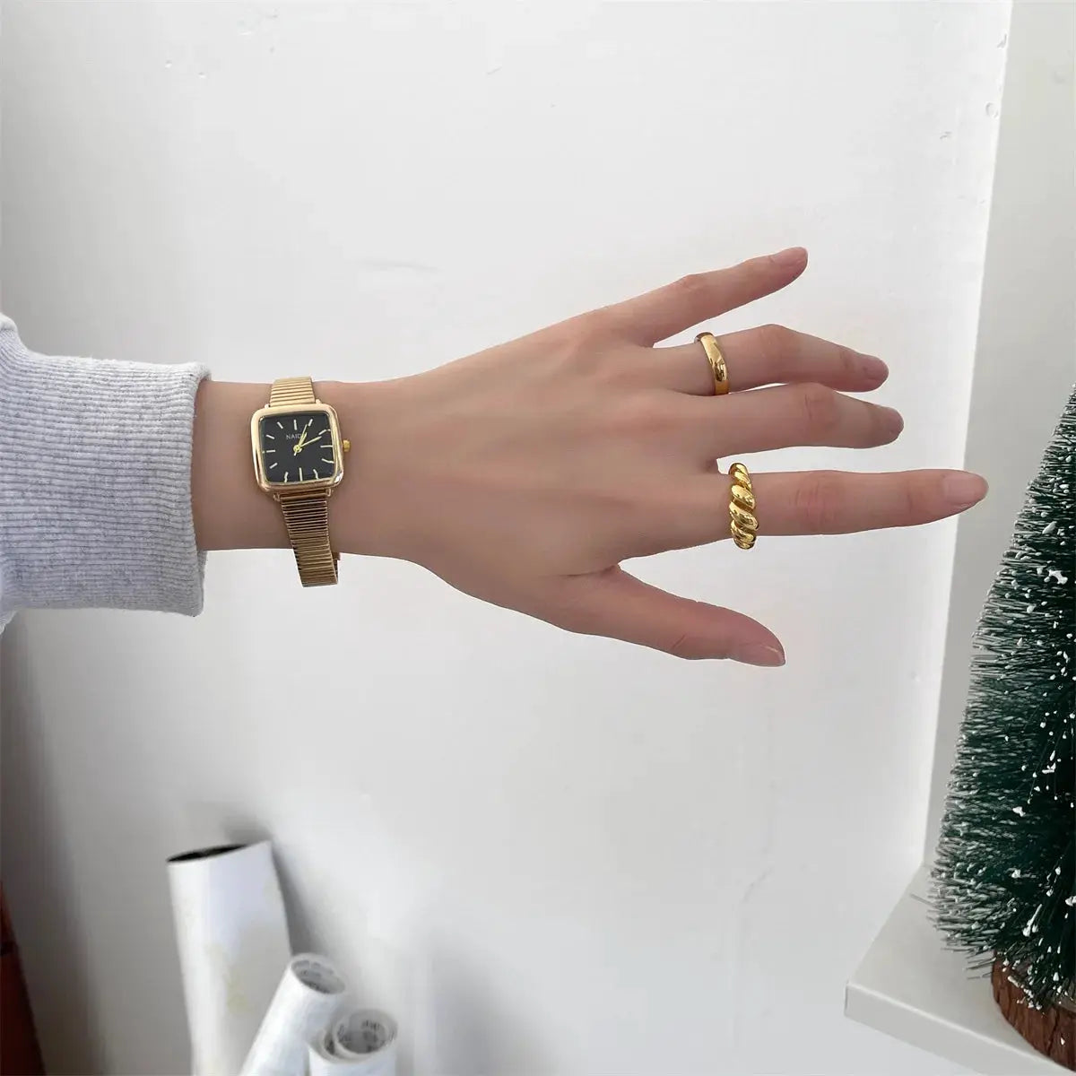 Gold-tone women's quartz wristwatch with black square dial and adjustable stainless steel strap