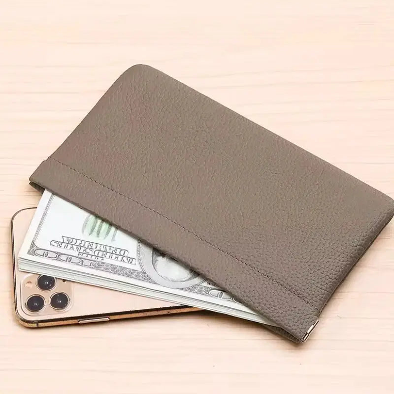 Self-closing brown artificial leather long wallet with cash and a smartphone beneath