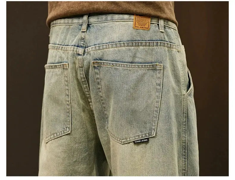 Men's light-wash denim jeans with large back pockets and brown leather patch