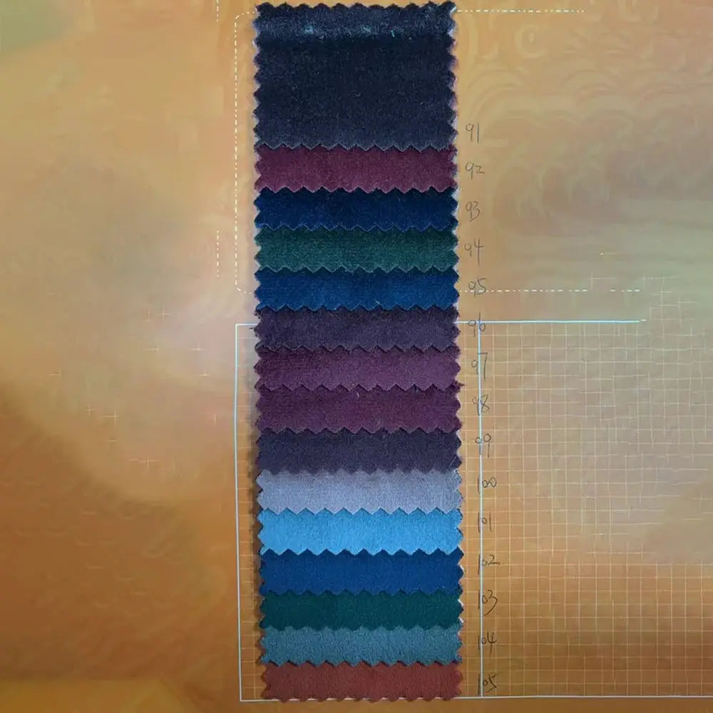 Velvet fabric swatch card displaying a vertical stack of color samples for a women's suit, with greens and blues.