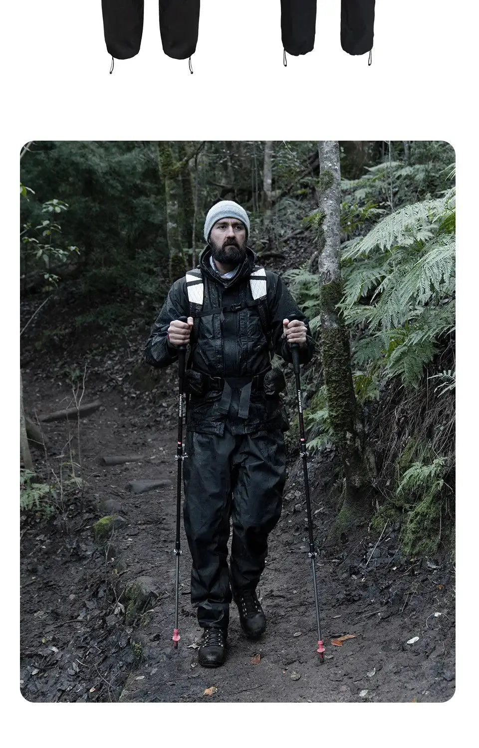 Naturehike rainproof pants; black waterproof hiking pants worn by a bearded hiker on a forest trail with trekking poles