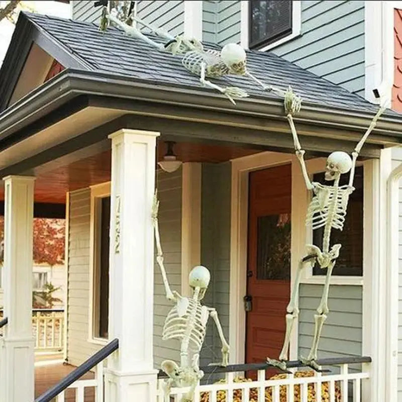 Three Halloween skeleton decorative props perched on porch railing for haunted-house decor.