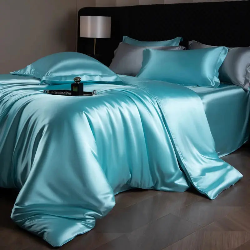 Silk bed sheet set in turquoise with duvet cover, fitted and flat sheets, and pillowcases.