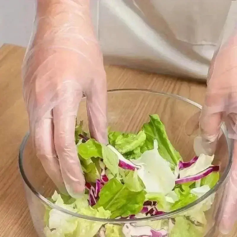 Disposable TPE gloves, clear powder-free, Simples Market, worn while tossing salad in a glass bowl.