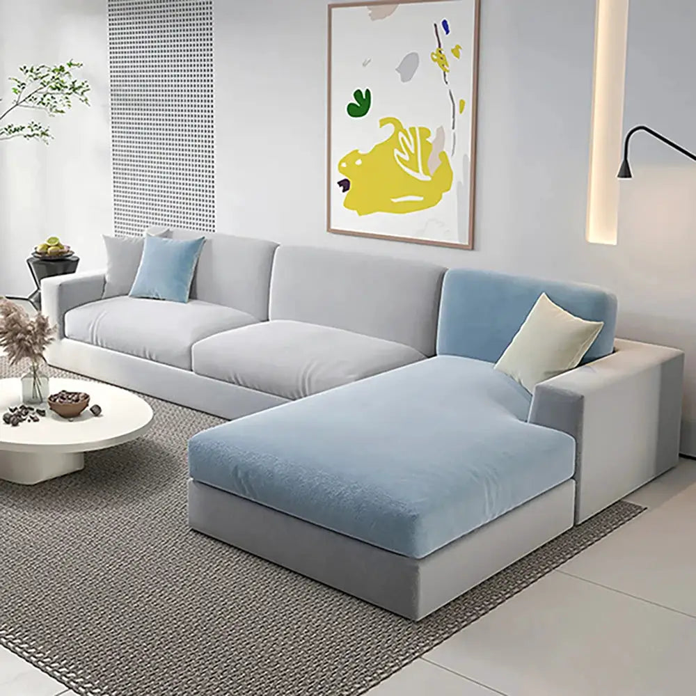 L-shaped sectional sofa with chaise; light blue velvet cushions on gray upholstery.