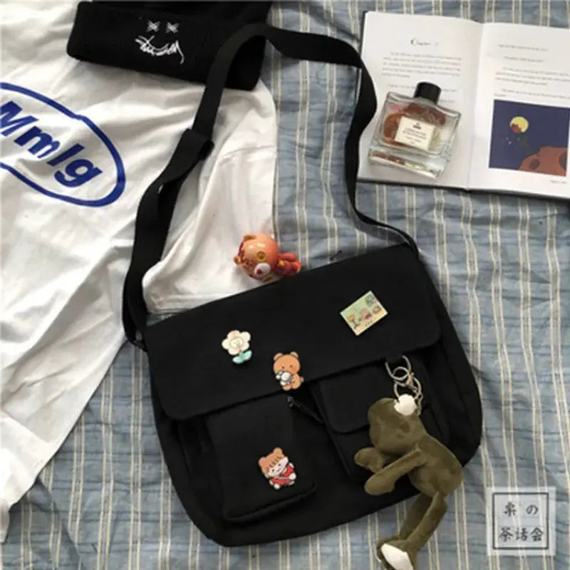 Women's black canvas messenger bag with cartoon patches and a plush keychain, crossbody bag