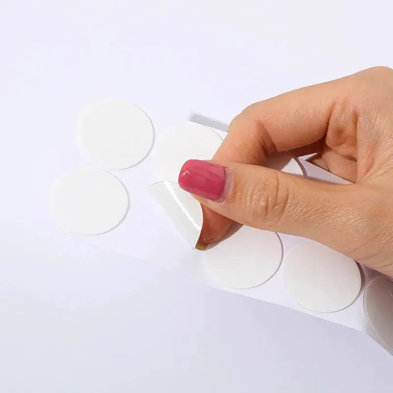 Round white calendar stickers on a peel-off sheet; hand peeling one off