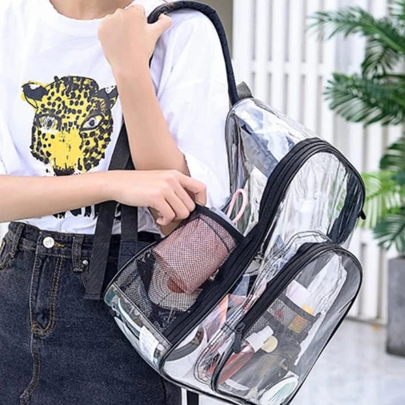Clear PVC backpack with black trim; large waterproof school bag with dual zip pockets and items visible inside.