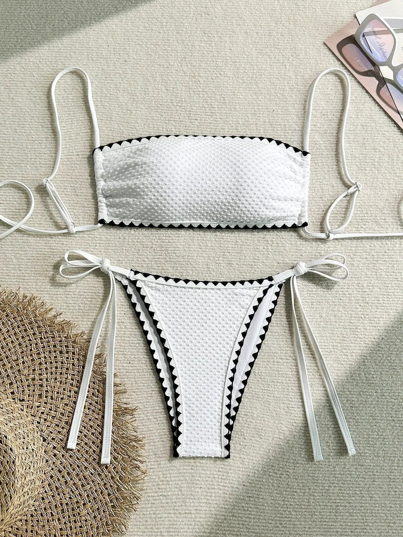White two-piece bikini set with strapless bandeau top and side-tie bottoms, textured fabric and black zigzag trim