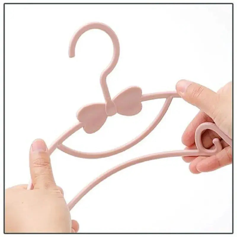 Baby clothes hanger with bow design, pink plastic, child-sized organizer