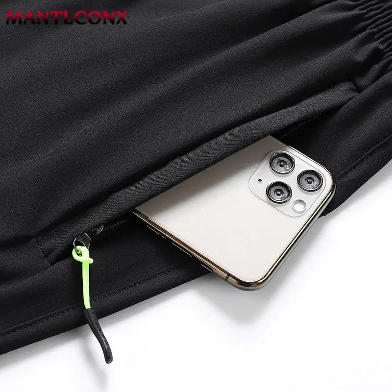 Black men's quick-dry jogging shorts with neon green zip tab, phone visible in pocket, lightweight breathable.