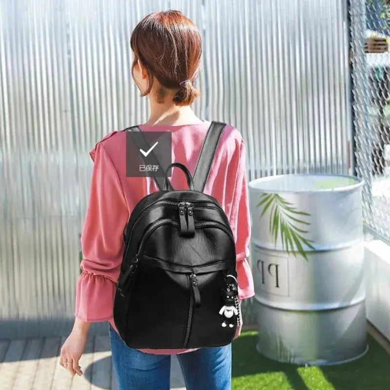 Women's black casual backpack with front zip pockets and panda charm keychain