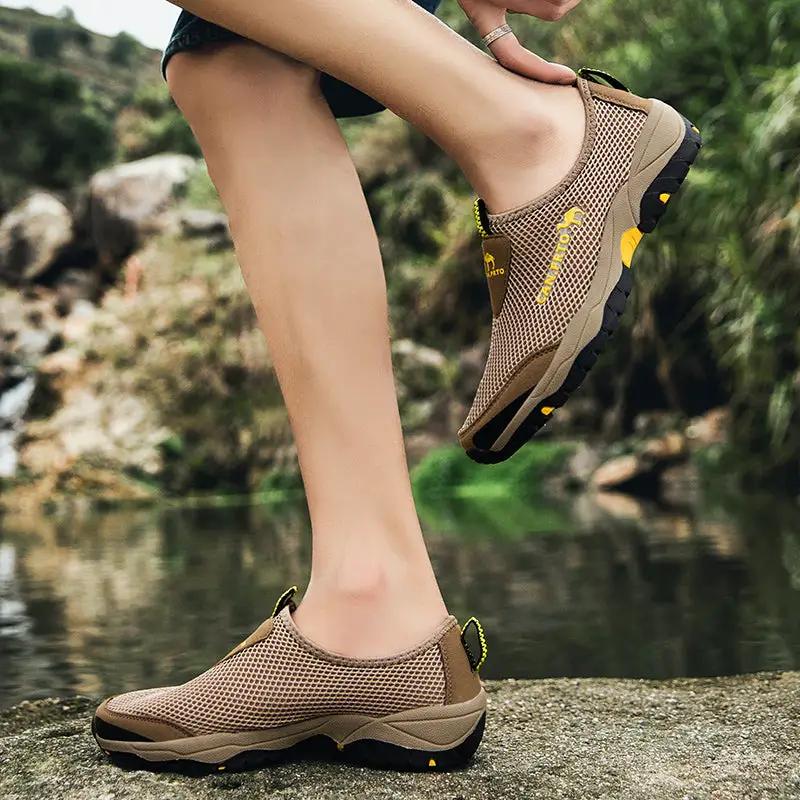 Tan breathable mesh slip-on sneakers for men with a rugged black sole and yellow accents; two shoes shown.