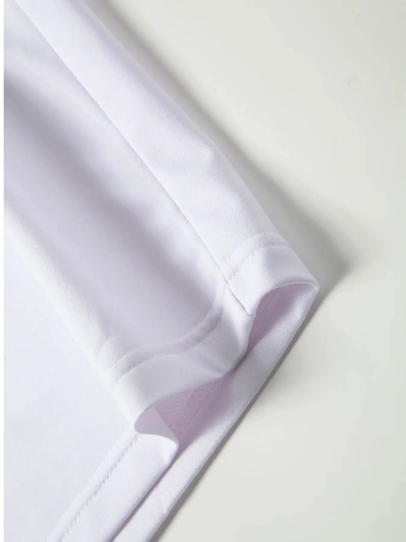 White shirt sleeve with rolled cuff; close-up shows smooth fabric and neat stitching