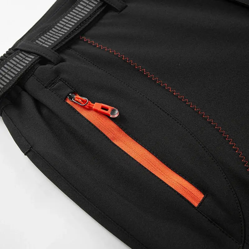 Men's JNLN thick warm fleece hiking pants, black soft-shell with orange zipper pocket.