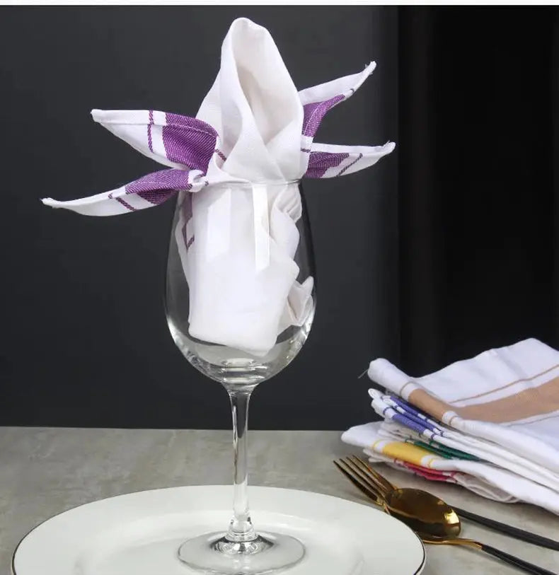 European kitchen towel placemat made of thick cotton cup cloth, with a white napkin folded inside a wine glass and purple ribbon.