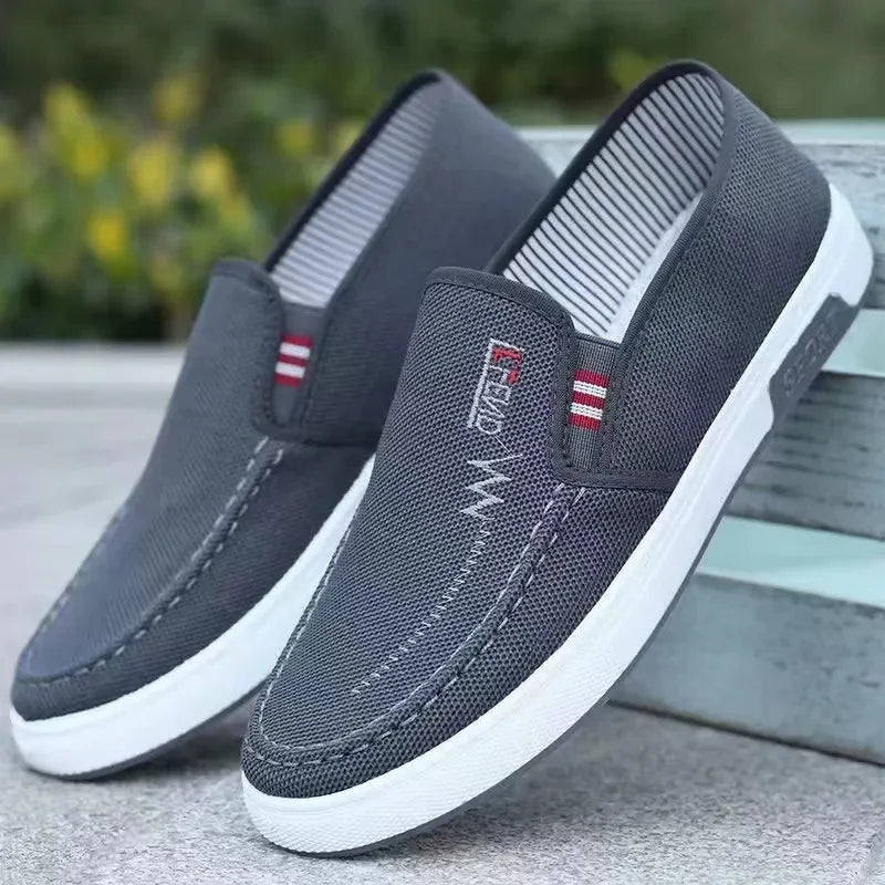 Pair of gray canvas slip-on sneakers with white soles and striped pull tabs